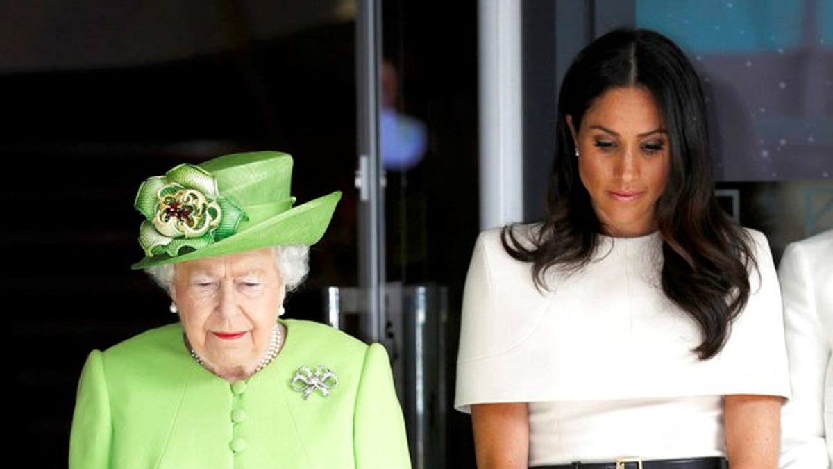 Britain's Queen Elizabeth and Meghan, Duchess of Sussex observe a moment of silence in memory of the victims of the Grenfell Tower fire during a to visit Storyhouse Chester, where they will be taken on a tour of the building before unveiling a plaque to mark the official opening, in Chester, England, Thursday, June 14, 2018. (Phil Noble/Pool Photo via AP)