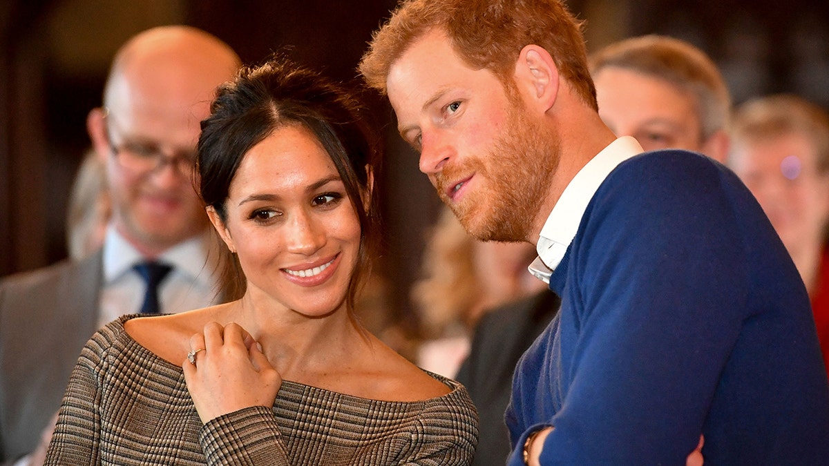 Britain's Prince Harry whispers to Meghan Markle as they watch a dance performance by Jukebox Collective in the banqueting hall during a visit to Cardiff Castle in Cardiff, Britain, January 18, 2018.