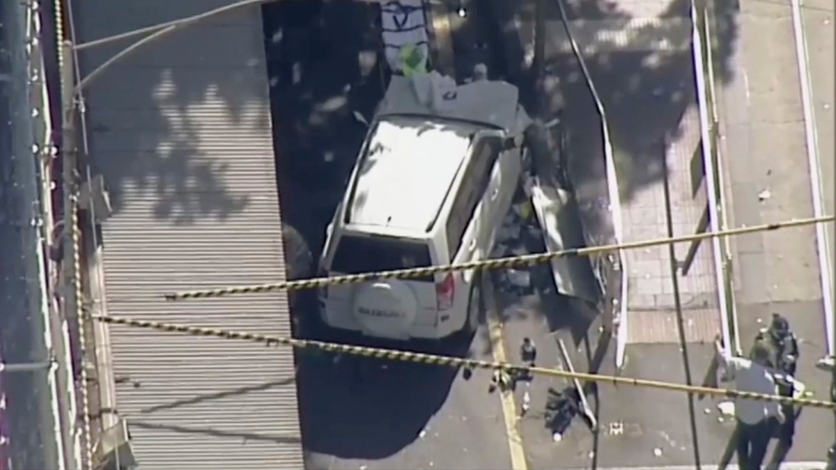 In this photo made video from the Australian Broadcasting Corp., a white SUV vehicle is stopped after allegedly striking pedestrians, Thursday, Dec. 21, 20217, in Melbourne, Australia. Local media say over a dozen people have been injured after a car drove into pedestrians on a sidewalk in central Melbourne. (Australian Broadcast Corp. via AP)