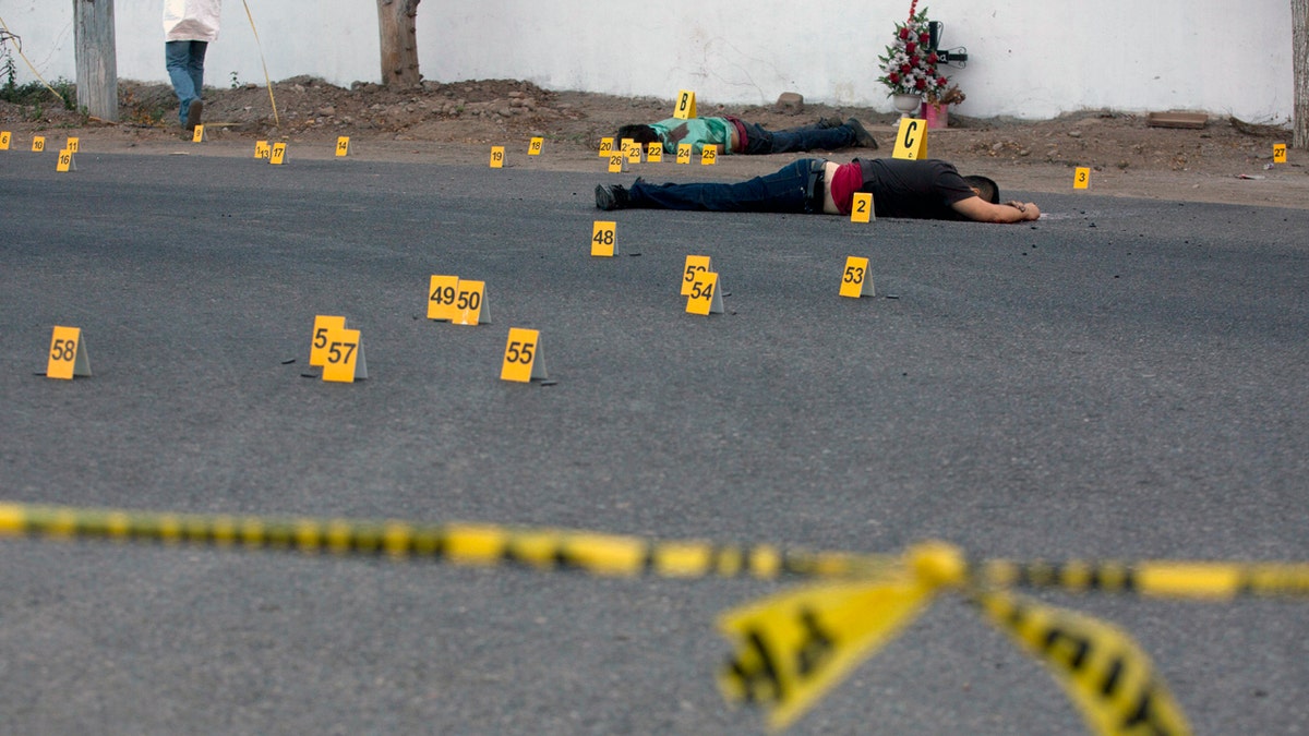 FILE - In this June 29, 2017 file photo, investigators mark the spot where spent bullet casing fell next several bodies lying on a road in the town of Navolato, Sinaloa state, Mexico. Five states in Mexico have gotten the sternest Ã¢â¬Ådo not travelÃ¢â¬Â advisories under a revamped U.S. State Department system unveiled Wednesday, Jan. 10 2017. The five include the northern border state of Tamaulipas and the Pacific coast states of Sinaloa, Colima, Michoacan and Guerrero, placing the states on the same level warning level as Somalia, Yemen, Syria or Afghanistan. (AP Photo/Enric Marti, File)