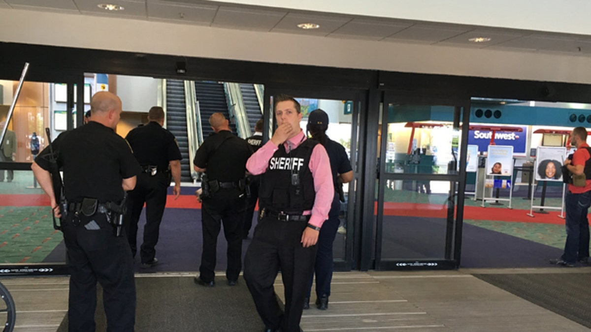 Police officers gather at a terminal at Bishop International Airport, Wednesday morning, June 21, 2017, in Flint, Mich. Officials evacuated the airport Wednesday, where a witness said he saw an officer bleeding from his neck and a knife nearby on the ground.  On Twitter, Michigan State Police say the officer is in critical condition and the FBI was leading the investigation. (Dominic Adams/The Flint Journal-MLive.com via AP)