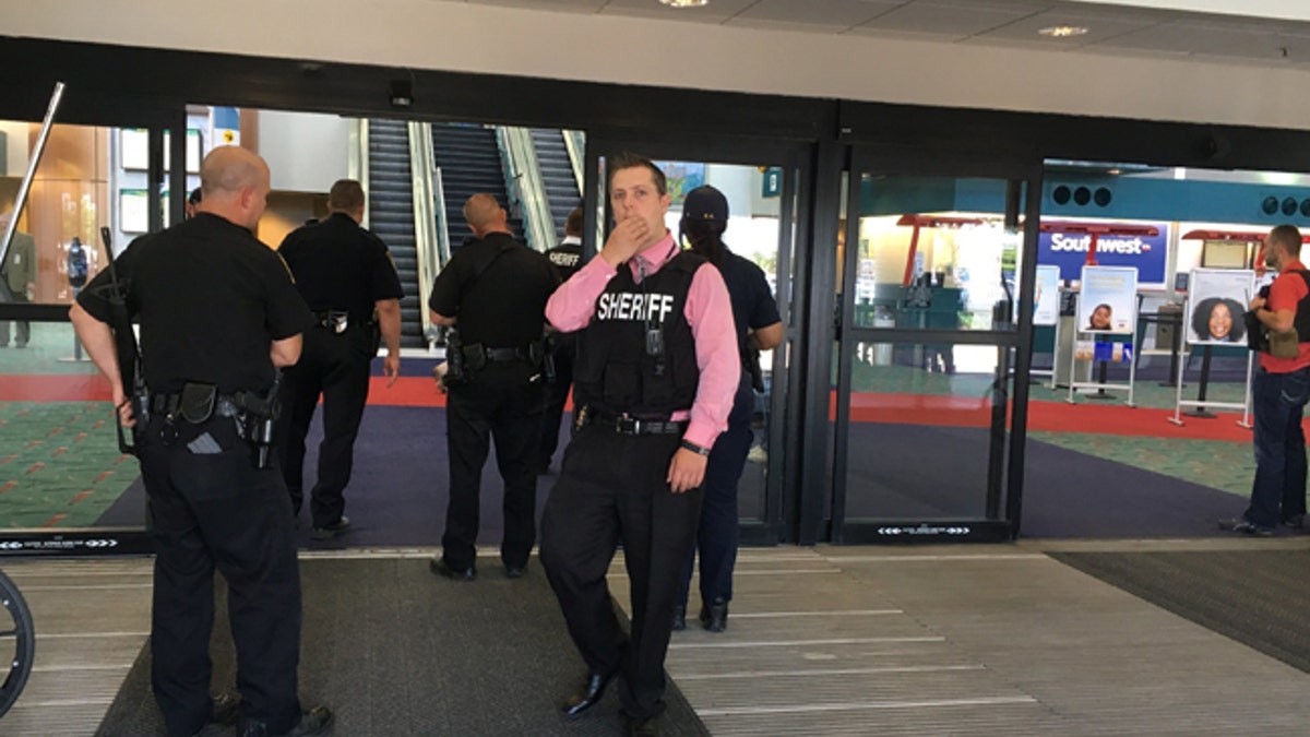 Police officers gather at a terminal at Bishop International Airport, Wednesday morning, June 21, 2017, in Flint, Mich. Officials evacuated the airport Wednesday, where a witness said he saw an officer bleeding from his neck and a knife nearby on the ground.  On Twitter, Michigan State Police say the officer is in critical condition and the FBI was leading the investigation. (Dominic Adams/The Flint Journal-MLive.com via AP)