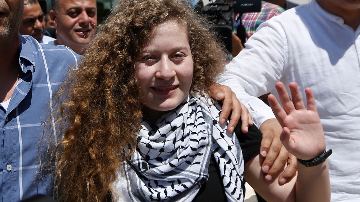 File - In this , Sunday, July 29, 2018 file photo, Ahed Tamimi waves after she visited the tomb of former Palestinian leader Yasser Arafat in the West Bank city of Ramallah. Tamimi family says they have been banned from traveling abroad. Her father, Bassem, said they were informed by the Palestinian Ministry of Civil Affairs they are barred by the Israeli Authorities from leaving. He said they were set to leave last week upon initiation by pro-Palestinian groups in Belgium, France and Spain. (AP Photo/Majdi Mohammed. File)