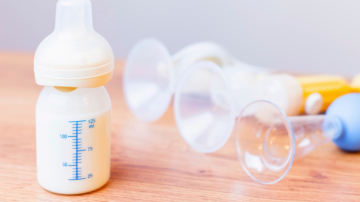 Baby bottle with milk and a measuring scale, manual breast pump, mothers breast milk is the most healthy food for newborn baby. Objects standing in a row. Selective focus