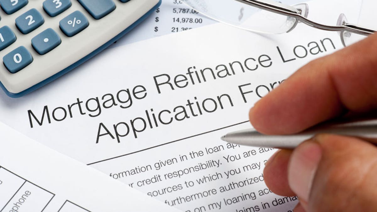Mortgage Refinance Application Form with pen, calculator, writing hand