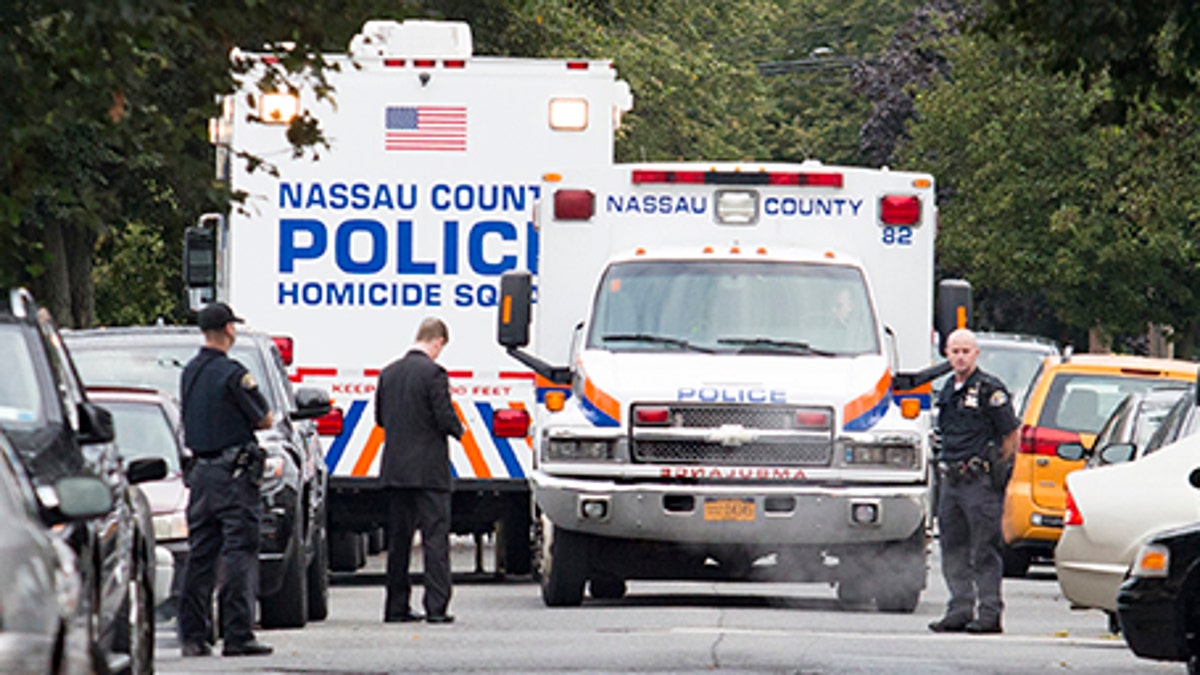 Nassau and Hempstead police investigate the scene of a homicide in Hempstead, N.Y., on Saturday, Aug. 12, 2017. Police on Long Island are searching or a "person of interest" in the killings of three women found inside a Hempstead home.A Nassau County Police spokesman says the women died from "blunt force trauma" injuries. A fourth woman survived and his being treated at a hospital. Detective Lt. Richard Lebrun did not identify the suspect police are seeking. He did not describe the suspect. (Howard Schnapp/Newsday via AP)