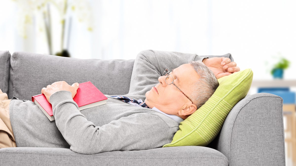 Senior man sleeping on sofa indoors