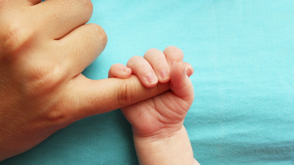 newborn baby with mom finger istock