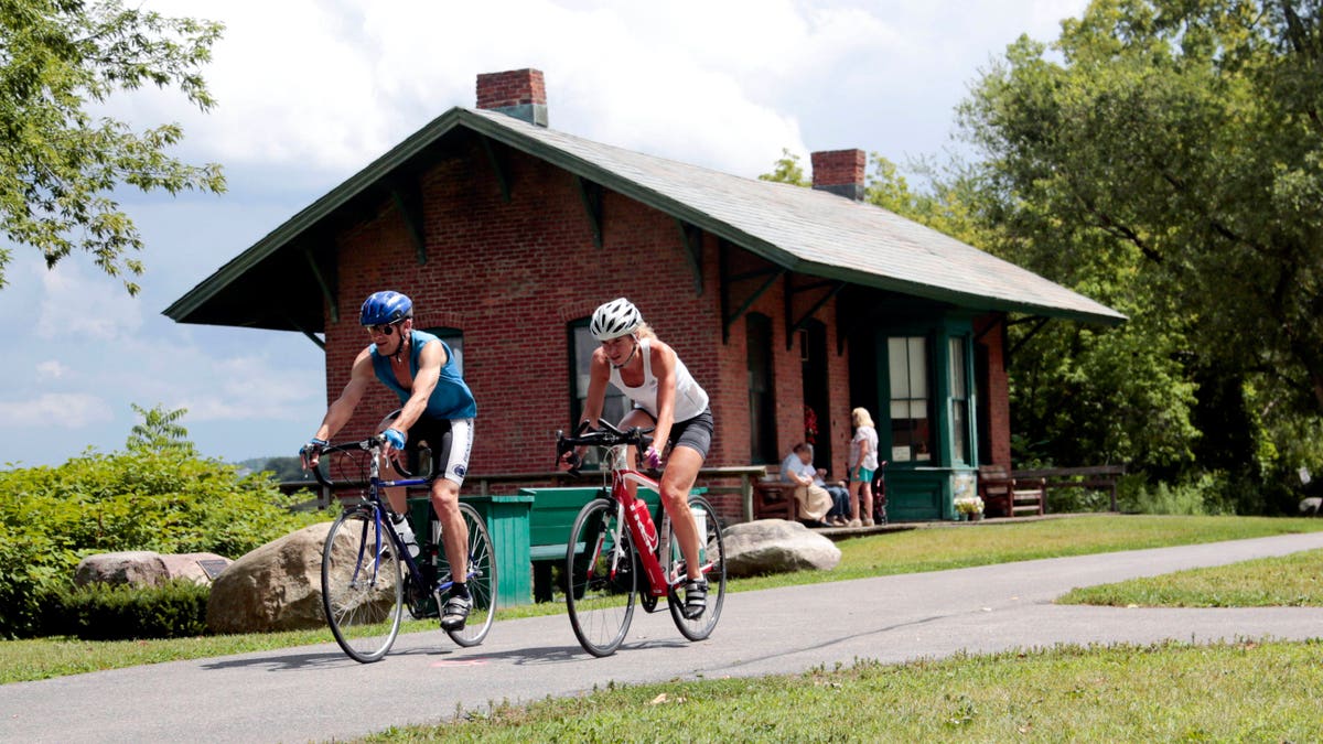 FILE- In this Tuesday, Aug. 4, 2015 file photo, cyclists pass the Niskayuna Train Station as they bike on the Canalway Trail in Niskayuna, N.Y. Gov. Andrew Cuomo proposed a a 750-mile paved biking and hiking Empire State Trail, of which the Canalway Trail would be part of. (AP Photo/Mike Groll, File)