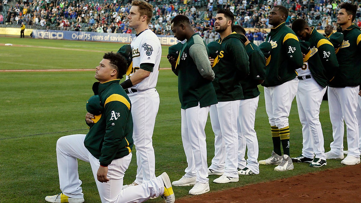 Oakland Athletics catcher Bruce Maxwell kneels during the National Anthem before the start of a baseball game against the Texas Rangers Saturday, Sept. 23, 2017, in Oakland, Calif. Bruce Maxwell of the Oakland Athletics has become the first major league baseball player to kneel during the national anthem. (AP Photo/Eric Risberg)