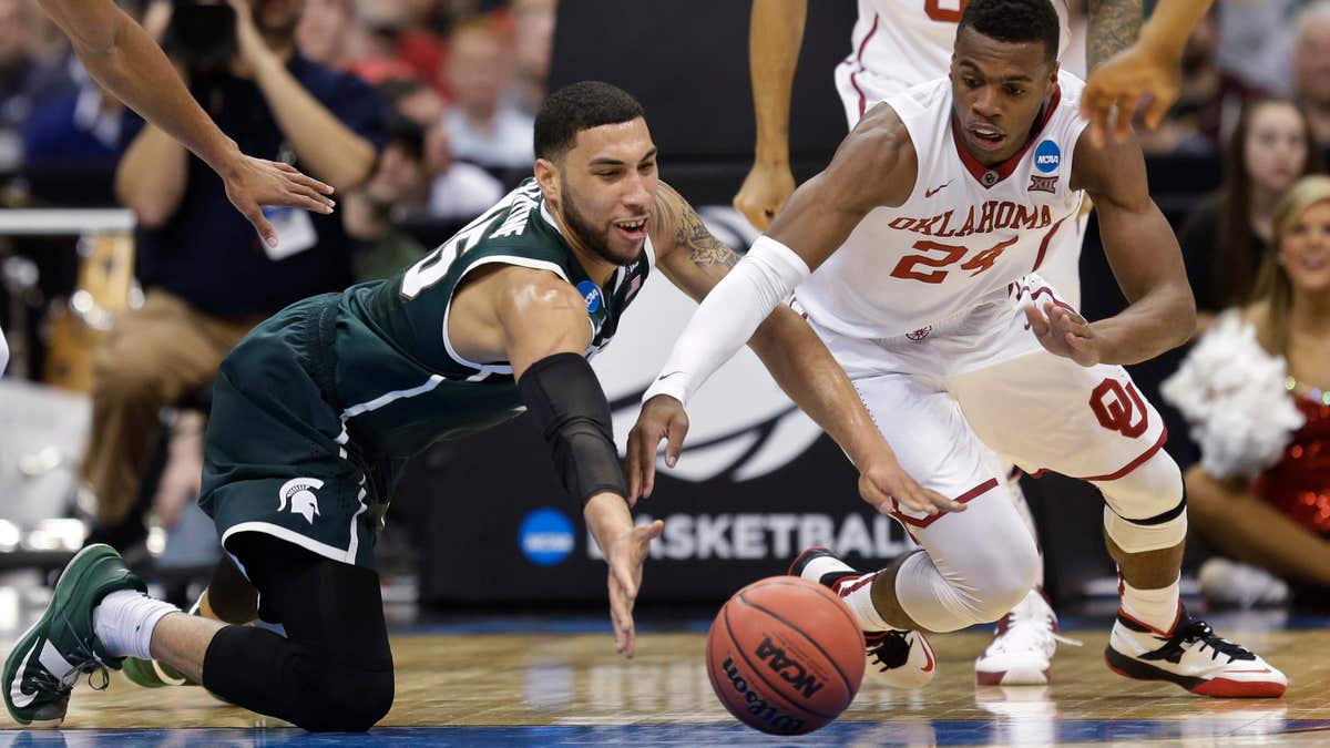 March 27, 2015: Michigan State's Denzel Valentine (45) and Oklahoma's Buddy Hield (24) dive for the ball during the first half of a regional semifinal in the NCAA men's college basketball tournament .