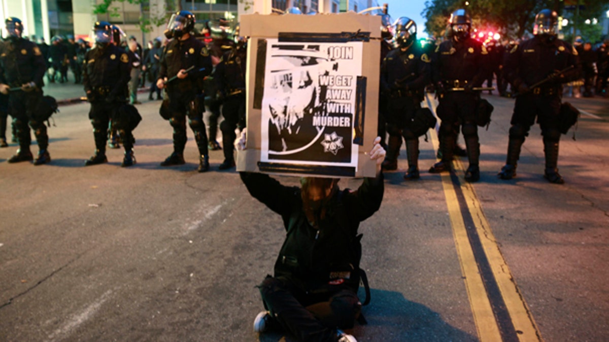 July 8: A demonstrator holds a sign in front of a moving police line in Oakland, Calif., after a guilty verdict for Johannes Mehserle. The former San Francisco Bay Area Rapid Transit police officer was found guilty in Los Angeles for shooting unarmed black man Oscar Grant on New Year's Day 2009 at a BART station in Oakland.