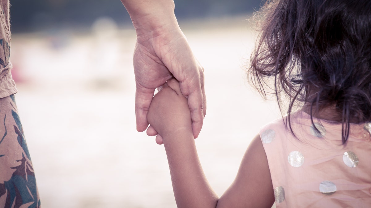 child cute little girl and mother holding hand together with love in vintage color filter