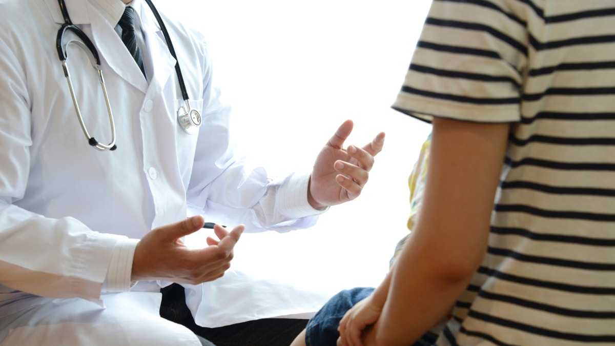 pediatrician with patient doctor explaining something to child istock