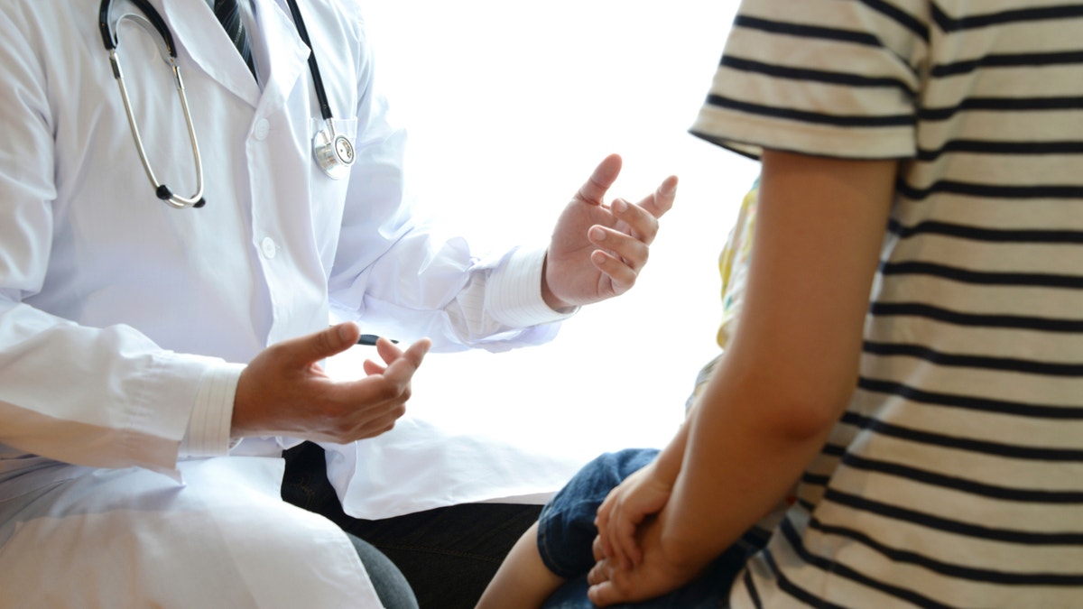 pediatrician with patient doctor explaining something to child istock