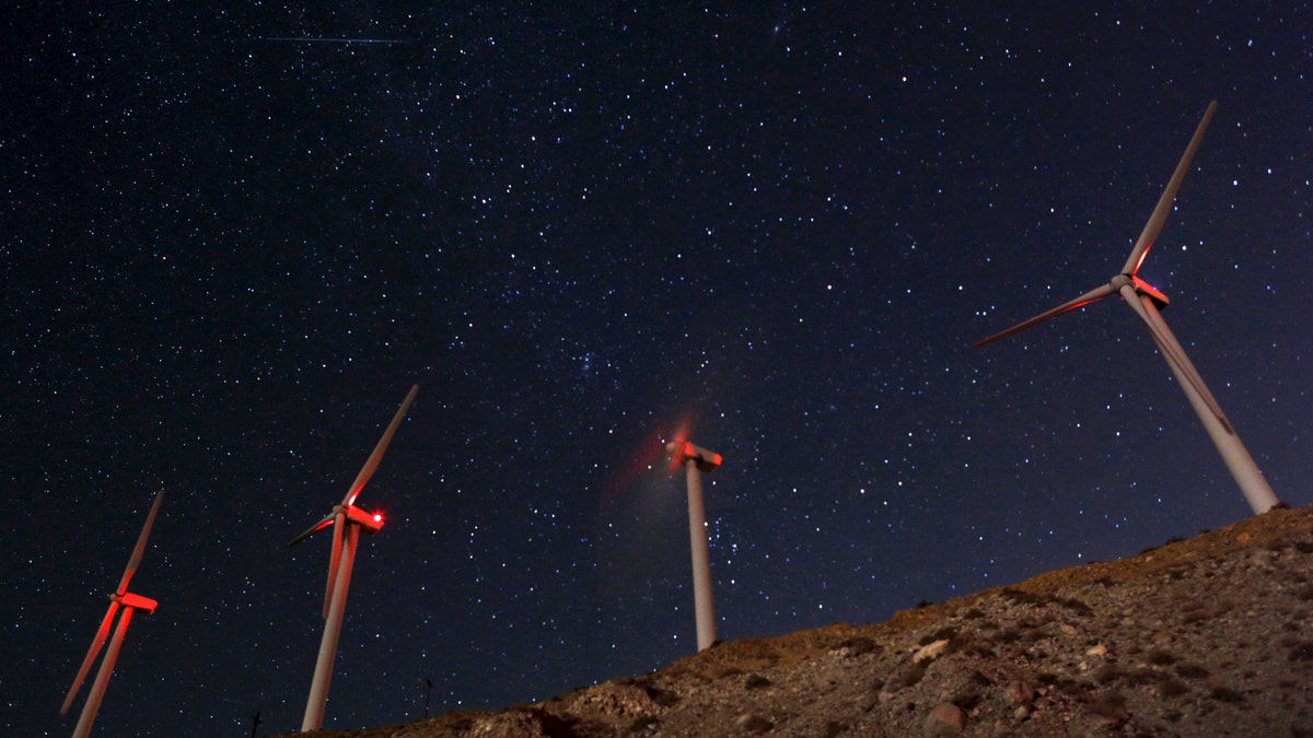 A meteor (top L) speeds past windmills at the San Gregornio Pass Wind Farm near Whitewater, California, August 13, 2015. The annual Perseid meteor shower is occurring during an upcoming new moon, making for stelar viewing conditions, according to NASA. REUTERS/Sam Mircovich - RTR4YZ6X