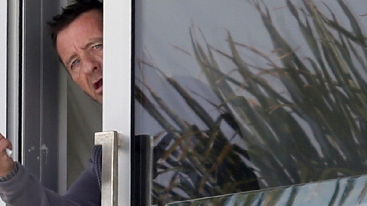 FILE - In this Nov. 6, 2014 file photo, Phil Rudd, drummer for the rock band AC/DC, gestures from a window at his house in Tauranga, New Zealand.  Rudd was the toast of this quiet New Zealand coastal community when he celebrated the launch of his surprise solo album at his marina restaurant, Phils Place. Even the mayor was there.  (AP Photo/New Zealand Herald, John Borren, File) NEW ZEALAND OUT, AUSTRALIA OUT