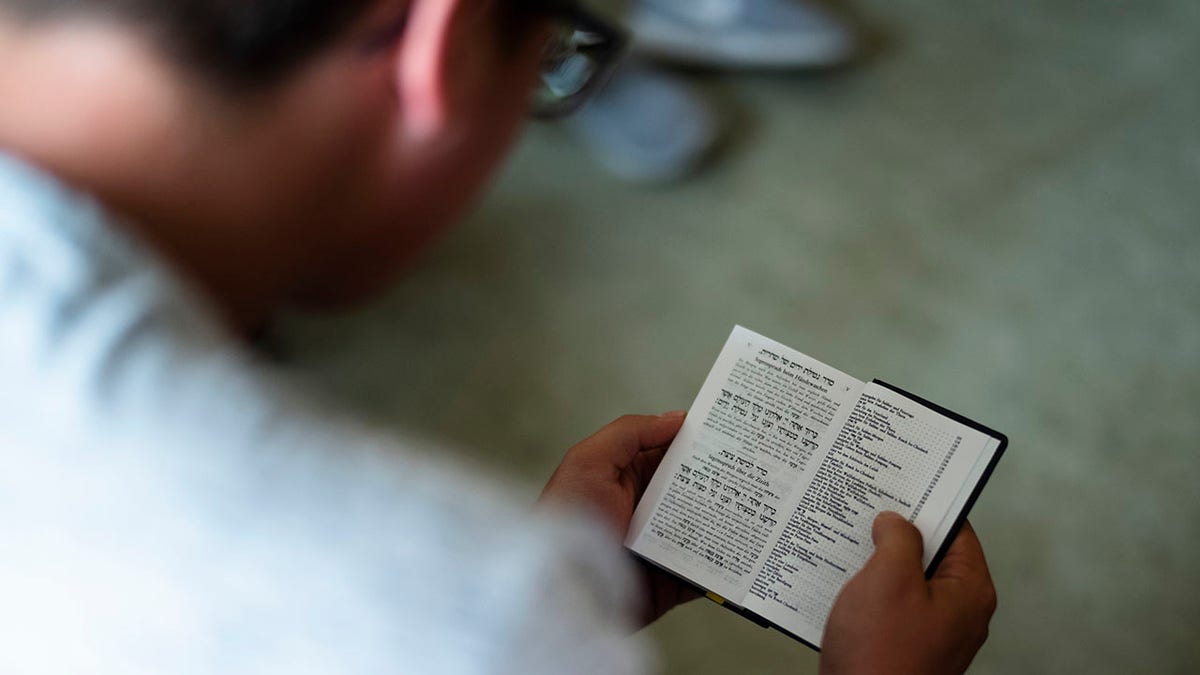 student reads in a Jewish prayer book during a lesson about Jewish life