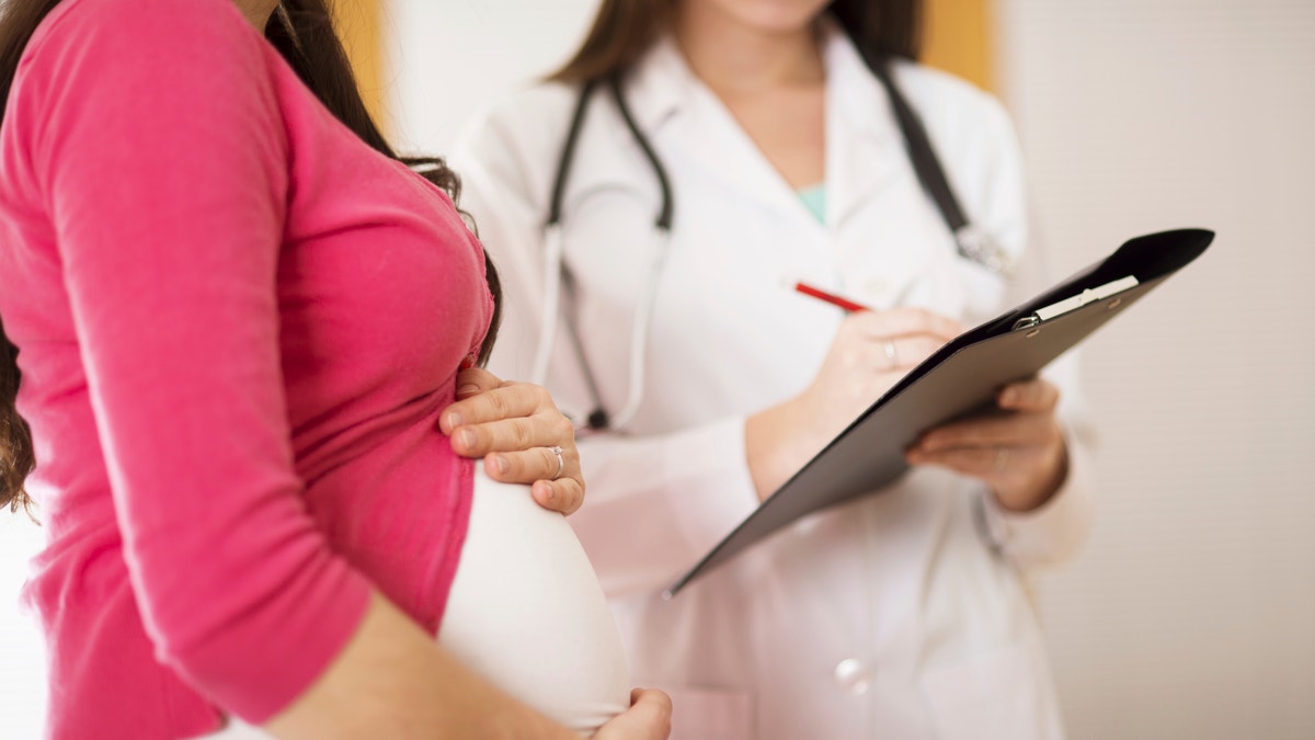 Young pregnant woman with doctor in ambulance.