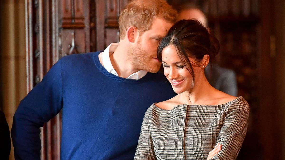 Britain's Prince Harry whispers to Meghan Markle as they watch a performance by a Welsh choir in the banqueting hall during a visit to Cardiff Castle in Cardiff, Britain, January 18, 2018.