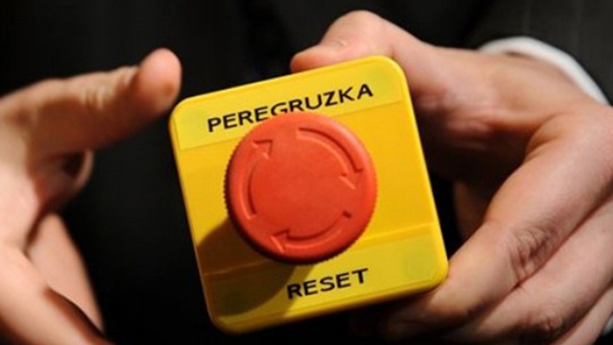 An assistant shows the mock 'reset' button that US Secretary of State Hillary Clinton handed over to Russian Foreign Minister Sergei Lavrov during a meeting in Geneva, Switzerland, Friday, March 6, 2009. Clinton handed Lavrov the block with a red button marked "reset" in English and "overload" in Russian, a reference to a speech by new US Vice-President Joe Biden in January signalling that the Obama administration wanted vastly improved ties with Russia. (AP Photo/Fabrice Coffrini, Pool)