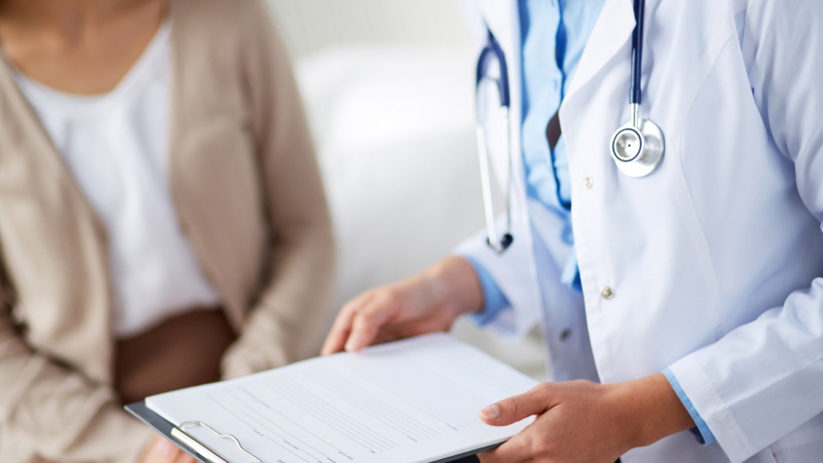 Female doctor holding application form while consulting patient