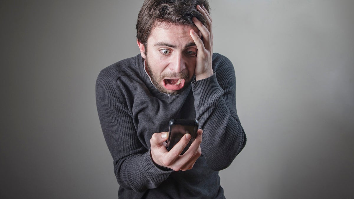 Shocked and frightened young caucasian man checking his phone, terrified with its content