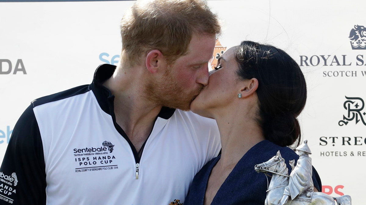 Meghan, Duchess of Sussex and Britain's Prince Harry kiss during the presentation ceremony for the Sentebale ISPS Handa Polo Cup at the Royal County of Berkshire Polo Club in Windsor, England, Thursday, July 26, 2018.(AP Photo/Matt Dunham)