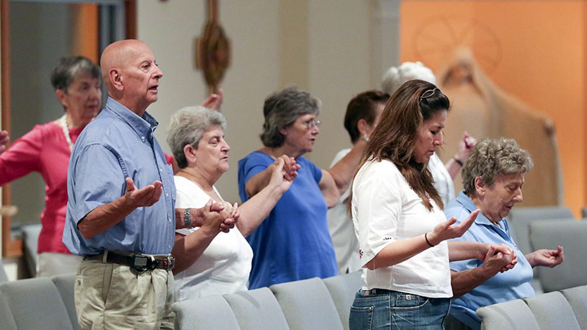 Parishioners join hands as they pray the