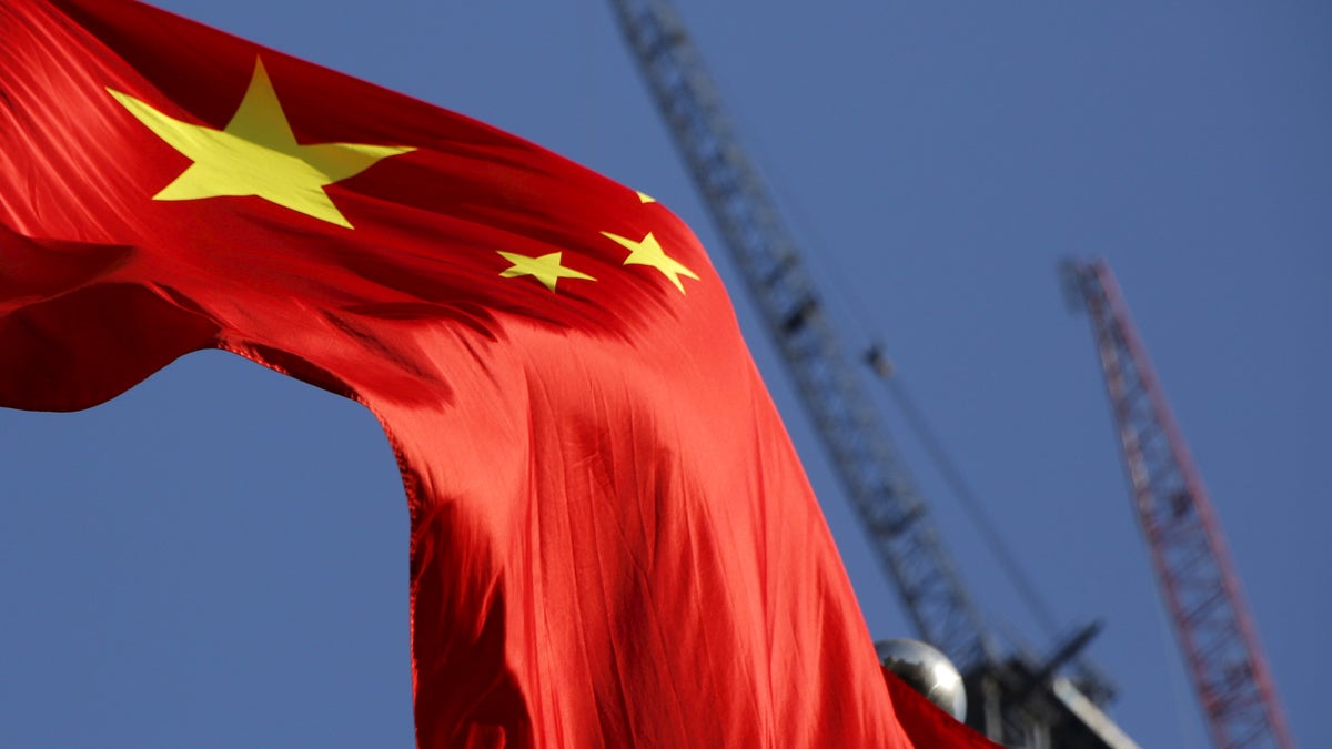 China's national flag is seen in front of cranes on a construction site at a commercial district in Beijing, China, January 26, 2016. REUTERS/Kim Kyung-Hoon - RTX240F5