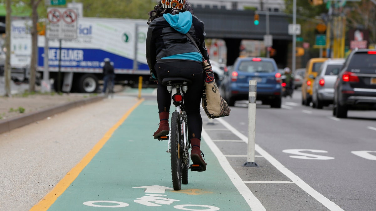 A woman rides a bicycle along a designated bike lane on Queens Boulevard in the borough of Queens in New York, U.S., May 5, 2016. REUTERS/Shannon Stapleton - RTX2E0NW