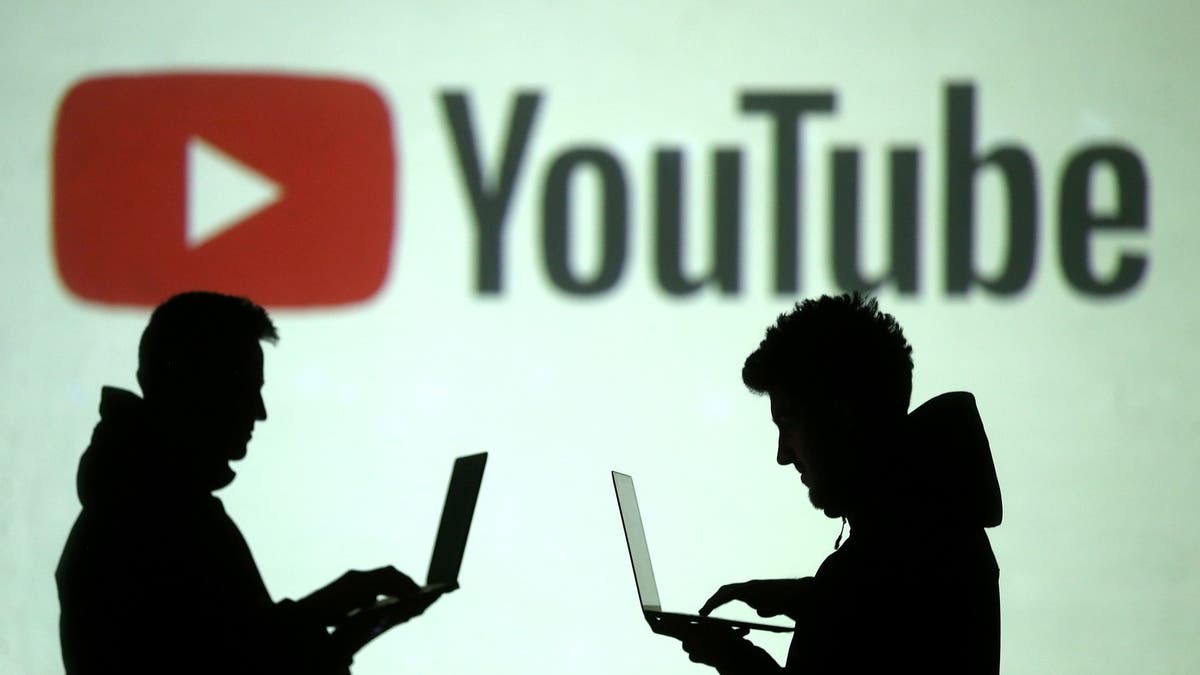 Silhouettes of mobile device users are seen next to a screen projection of Youtube logo in this picture illustration taken March 28, 2018.  REUTERS/Dado Ruvic/Illustration - RC1502FFC0B0