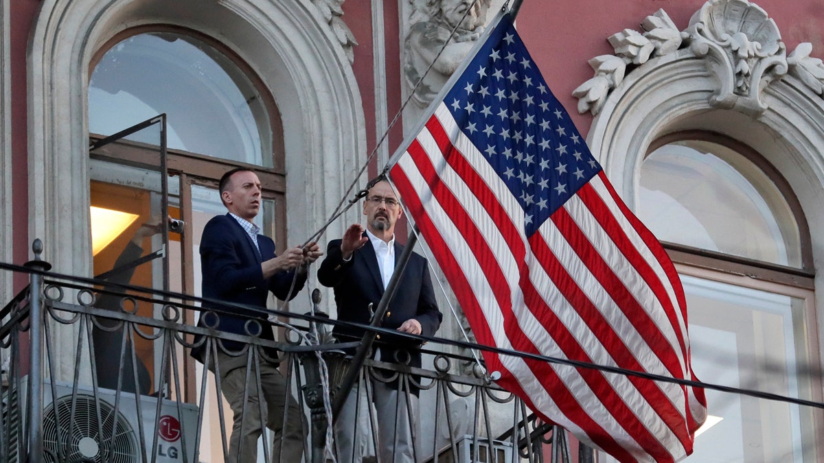 Consulate employees remove the U.S flag at the U.S. consulate in St.Petersburg, Russia, Saturday, March 31, 2018. Russia announced the expulsion of more than 150 diplomats, including 60 Americans, on Thursday and said it was closing a U.S. consulate in retaliation for the wave of Western expulsions of Russian diplomats over the poisoning of an ex-spy and his daughter in Britain, a tit-for-tat response that intensified the Kremlin's rupture with the United States and Europe. (AP Photo/Dmitri Lovetsky)