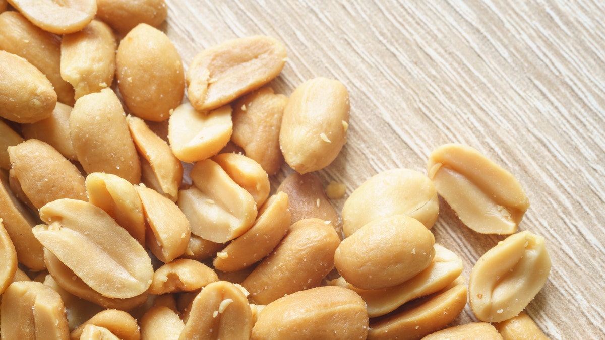 Closeup on roasted salted peanuts, wooden background, diagonal composition