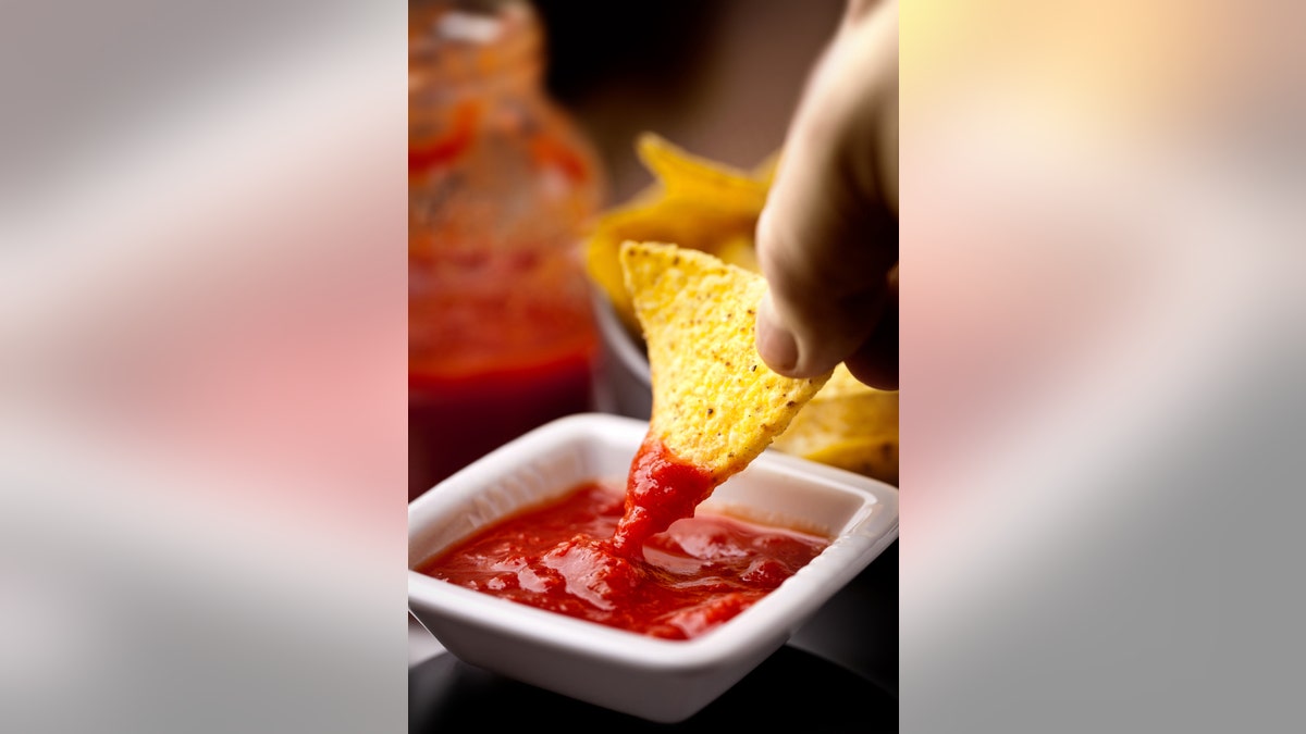 corn chips diping into red salsa