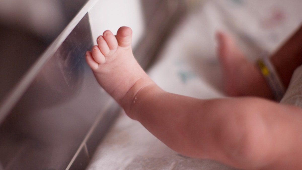 Tiny foot of a newborn human baby with a soft focus.