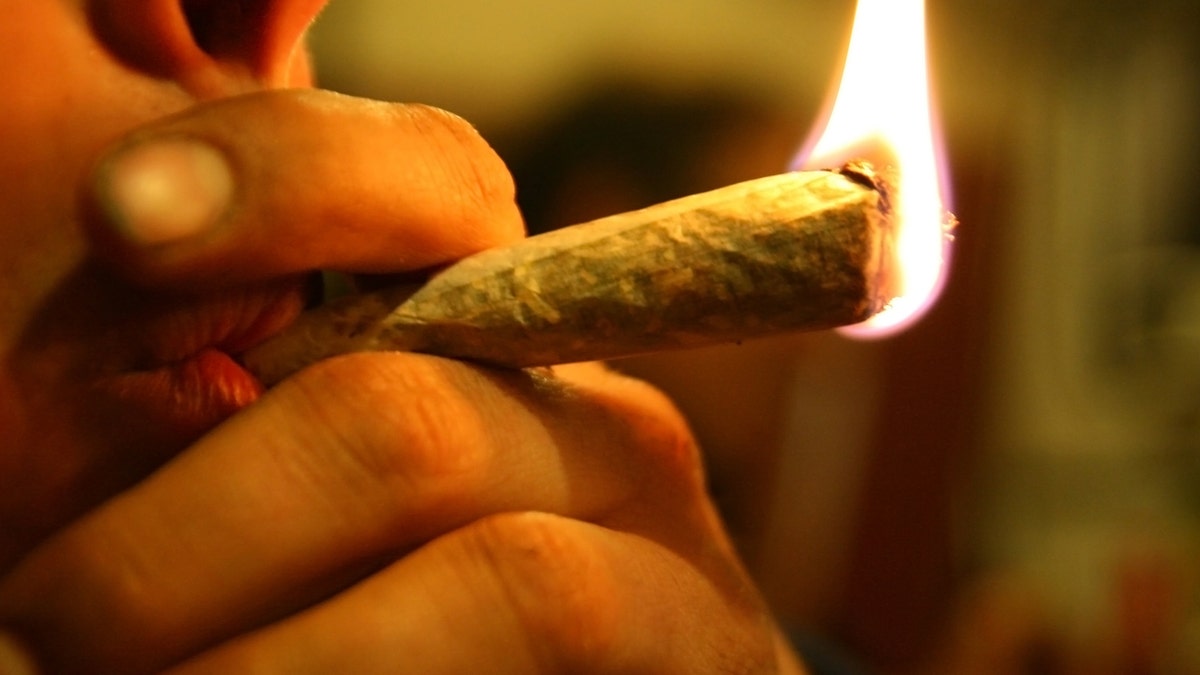 Marijuana joint on fire, in the lips