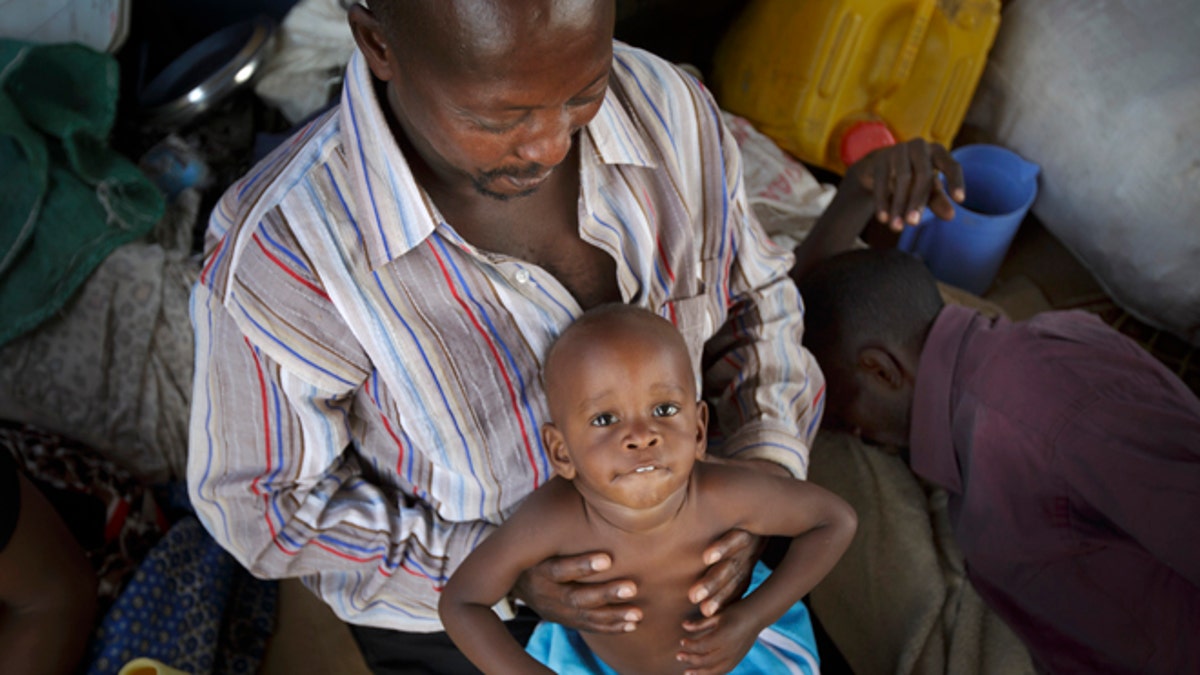 Dec. 30, 2013: A displaced Ugandan boy is held by a relative as they wait for an evacuation flight from the United Nations camp where they have sought shelter in Malakal, South Sudan. When violence broke out in Juba on Dec. 15 life remained calm but tense in Malakal, the capital of oil-producing Upper Nile state, but the violence then radiated outward from Juba and full-fledged war broke out in the town on Christmas Day, as army commanders defected and pledged allegiance to the country's ousted vice president, in most cases pitting the ethnic group of President Salva Kiir, a Dinka, against ethnic Nuers. (AP/Ben Curtis)