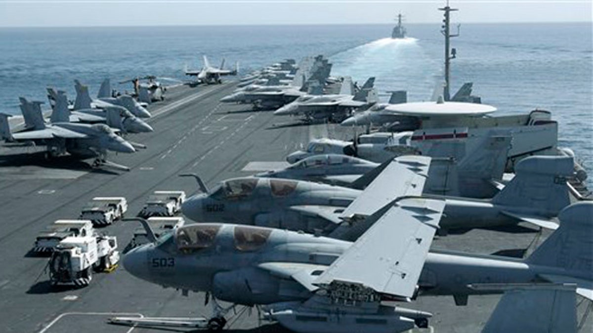 Feb. 14, 2012: A photo taken from the bridge of the Nimitz-class aircraft carrier USS Abraham Lincoln (CVN 72) shows US aircraft parked on the flight deck of a US destroyer, background, patrols the Arabian sea in the Strait of Hormuz. 