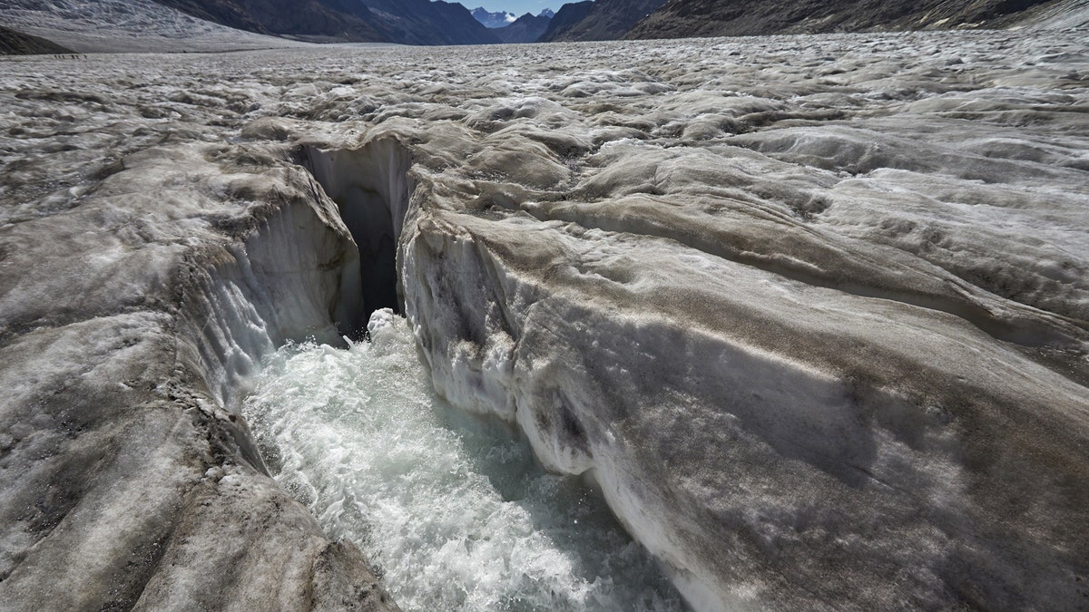 Water from the melting glacier runs down through a hole in the Aletsch Glacier on the Jungfraufirn Glacier, Switzerland, August 28, 2015. One of Europe's biggest glaciers, the Great Aletsch coils 23 km (14 miles) through the Swiss Alps - and yet this mighty river of ice could almost vanish in the lifetimes of people born today because of climate change. The glacier, 900 metres (2,950 feet) thick at one point, has retreated about 3 km (1.9 miles) since 1870 and that pace is quickening.  REUTERS/Denis Balibouse??PICTURE 10 OF 31 FOR WIDER IMAGE STORY 