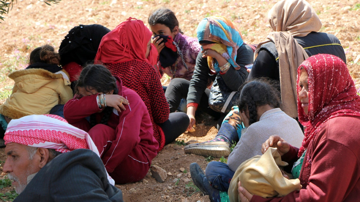 Syrians fleeing fighting between Turkish troops and Syrian Kurdish militia rest in a field between Afrin and Azaz, northwestern Syria, Wednesday, March 14, 2018. Turkish President Recep Tayyip Erdogan said on Wednesdat he hopes Afrin, at the center of the Syrian Kurdish district with the same name, will be totally encircled by the end of the day. Thousands of people had started to flee Afrin as the Turkish troops got closer, heading toward nearby government-controlled areas. But residents say they have come under fire. (DHA-Depo Photos via AP)