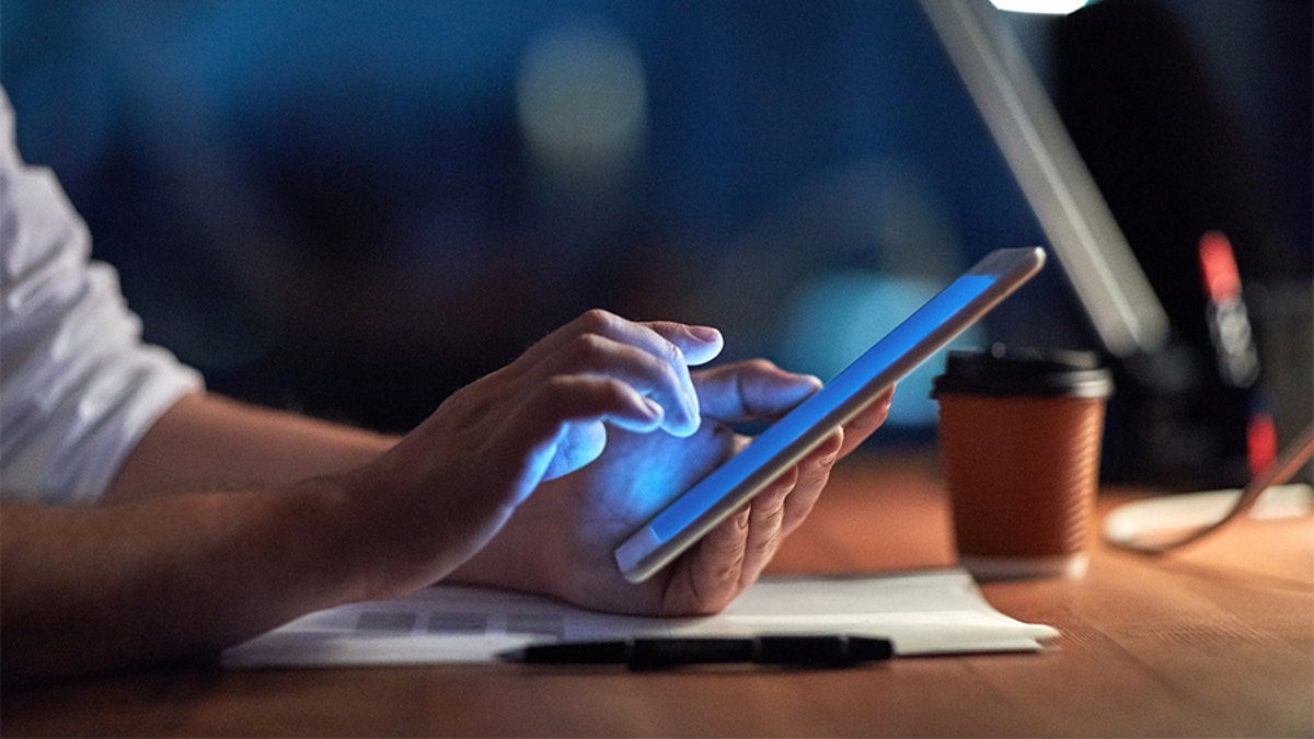 Cropped shot of a businessman using a digital tablet at night in an office