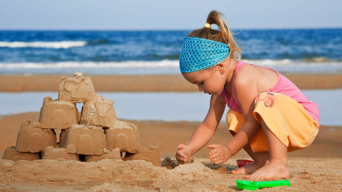 The child builds a sand castle on the beach