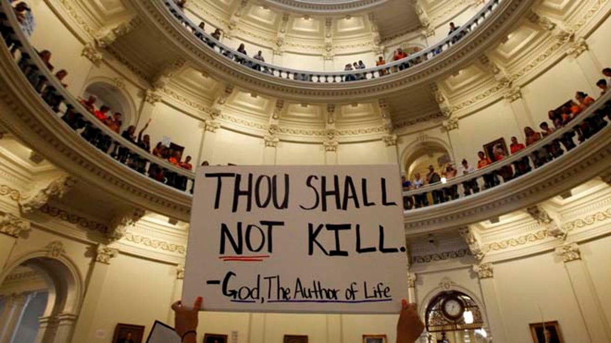 July 12, 2013: An anti-abortion protester holds a placard as protesters line the railing on the second floor of the rotunda of the State Capitol as the state Senate meets to consider legislation restricting abortion rights in Austin, Texas.