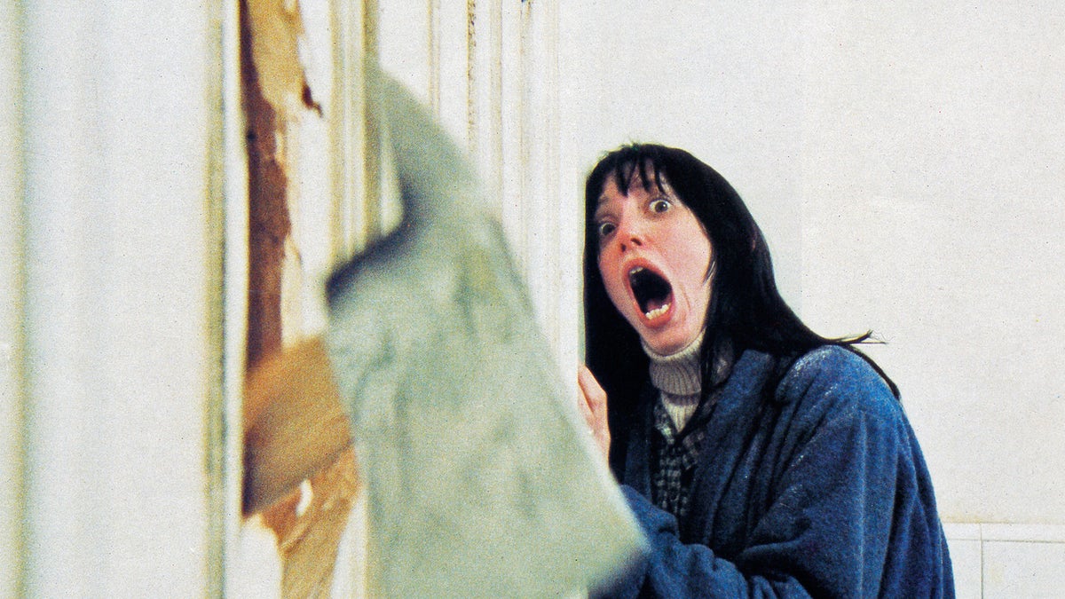 actress Shelley Duvall, recoils in shock as her husband chops through the bathroom door with a fire axe in a scene from 'The Shining', directed by Stanley Kubrick