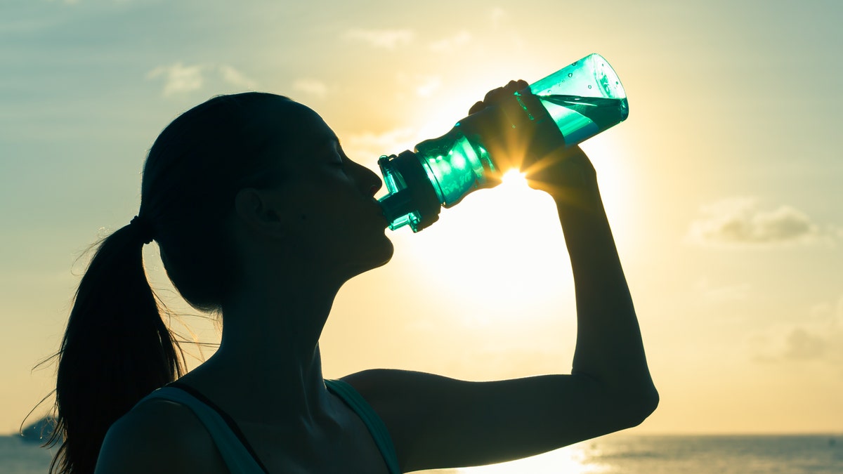 thirsty woman drinking water bottle istock