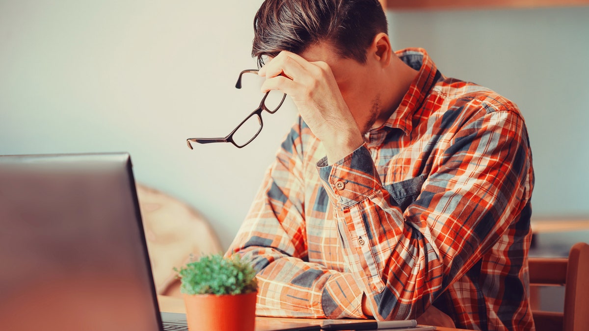 Tired young man sitting over laptop in the office