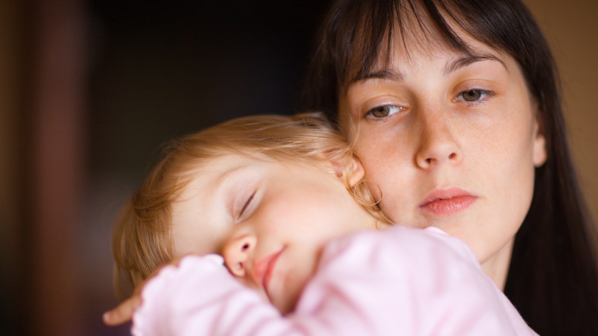 Sleepy little child with mom - shallow DOF, focus on woman's eyes