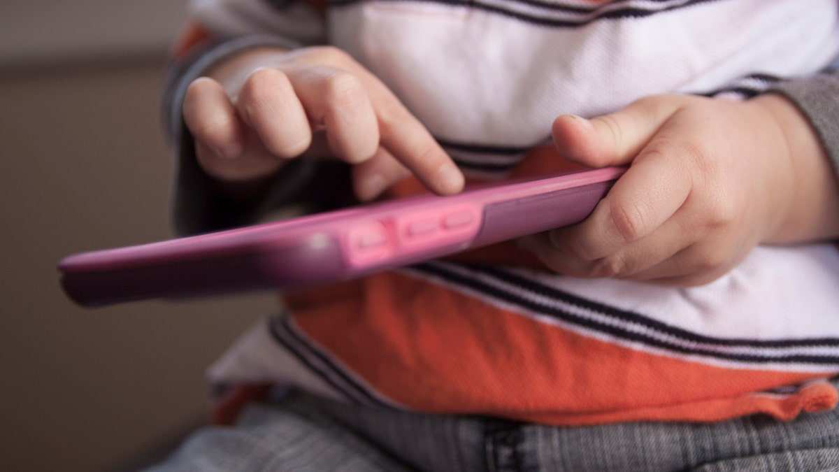 A toddler swipes the screen of a smart phone