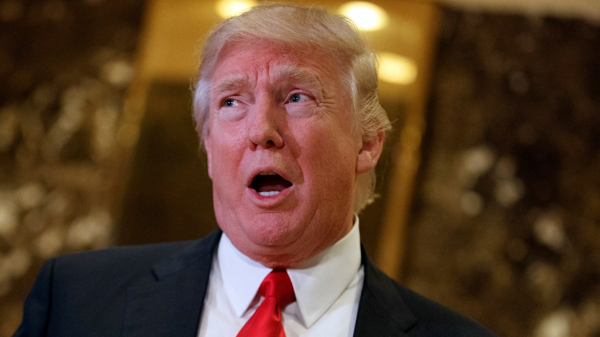 In this Jan. 13, 2017, photo, President-elect Donald Trump speaks with reporters in the lobby of Trump Tower in New York. Trumps meetings this week with CEOs seeking federal approval for major mergers are raising red flags for ethics lawyers concerned that about the possible erosion of a firewall between the regulators tasked with approving the billion-dollar deals and the White House. (AP Photo/Evan Vucci)